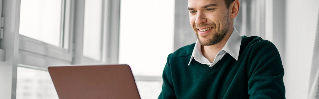man sitting behind desk with open laptop computer