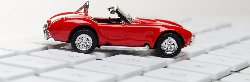 red toy car sitting on white computer keyboard